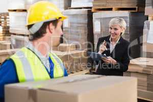 Warehouse worker holding box with manager behind him