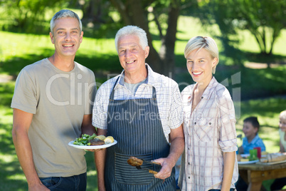 Happy couple with grandfather doing barbecue