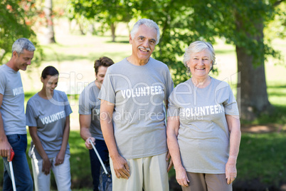 Happy volunteer senior couple smiling at the camera