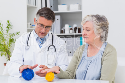Physiotherapist guiding female patient with massage ball