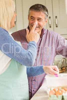 Happy woman putting flour on husbands nose