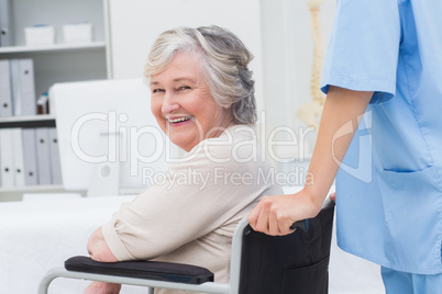 Senior patient in wheelchair being pushed by nurse