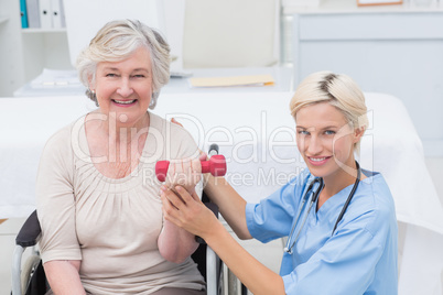 Nurse assisting female patient in lifting dumbbell