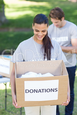 Happy volunteer brunette holding donation box