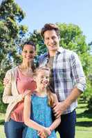 Happy family smiling at camera in the park