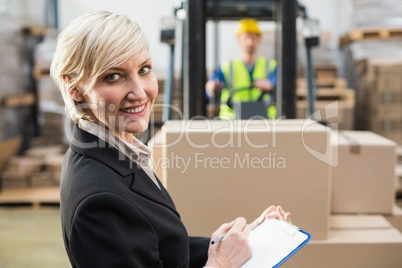 Warehouse manager writing on clipboard