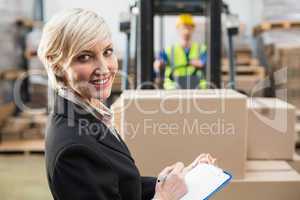 Warehouse manager writing on clipboard