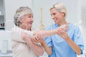 Happy nurse assisting patient in raising arm