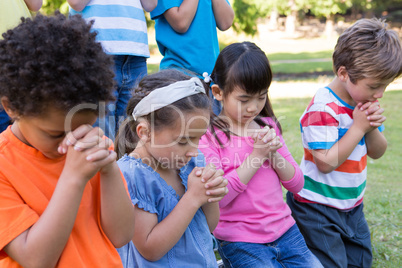 Children saying their prayers in park