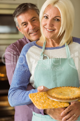 Mature blonde holding fresh pie with husband hugging her