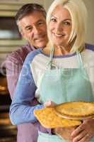 Mature blonde holding fresh pie with husband hugging her