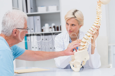 Senior patient showing spine problems to doctor at table
