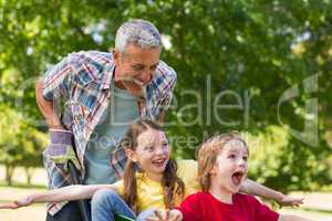 Happy father and his children playing with a wheelbarrow