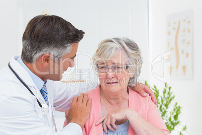 Doctor consoling senior patient in clinic