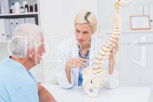 Doctor explaning spine model to senior patient
