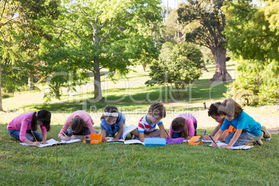School children doing homework on grass