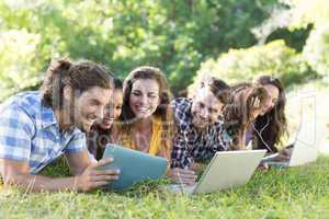 Smiling friends in the park using tablet pc and laptop