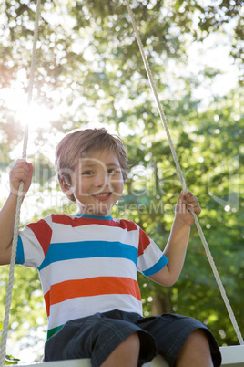 Happy little boy on a swing in the park