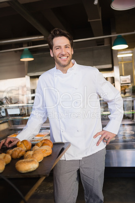 Happy baker standing near tray with bread