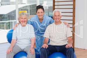 Female trainer with arms around senior couple