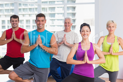 People practicing tree pose in fitness studio