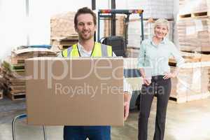 Smiling warehouse worker carrying box