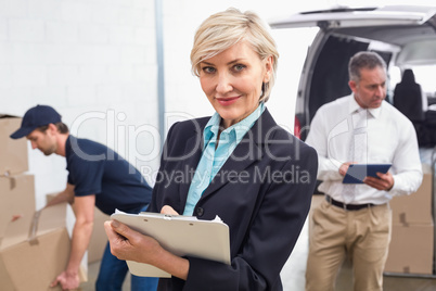 Smiling manager holding clipboard in front of his colleagues