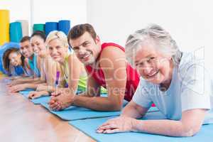 Senior woman with friends lying on exercise mats at gym