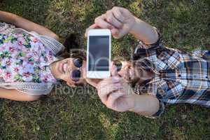 Young couple lying on grass taking selfie