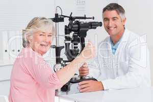 Senior patient gesturing thumbs up while sitting with optician