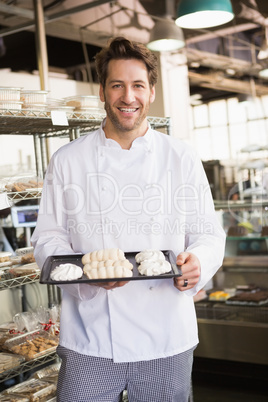 Smiling baker holding meringue tray