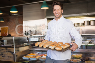 Happy baker showing tray with bread