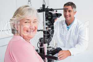 Senior woman smiling while sitting with optician