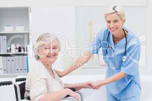 Friendly nurse holding senior patients hand