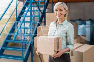 Smiling warehouse manager holding cardboard box