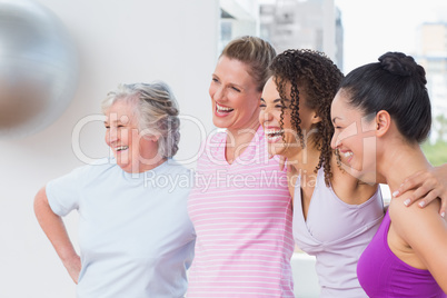 Friends standing arms around in fitness studio