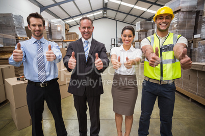 Warehouse team smiling at camera showing thumbs up