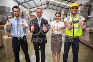 Warehouse team smiling at camera showing thumbs up