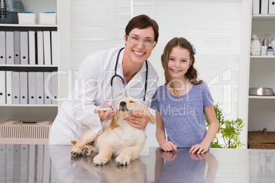 Smiling vet examining a dog with its owner