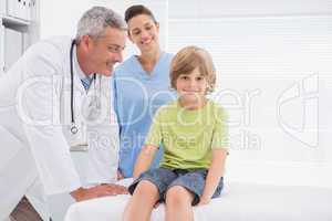 Little boy smiling at camera with doctors