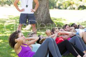 Fitness group doing sit ups in park with coach
