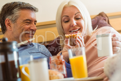 Happy mature couple having breakfast in bed