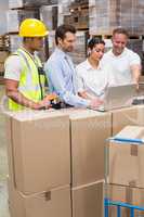 Warehouse managers and worker looking at laptop