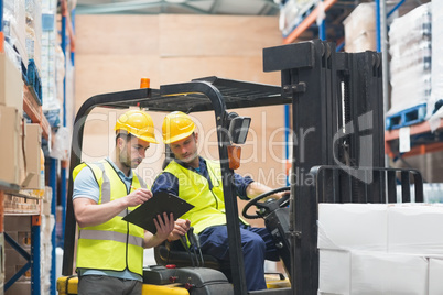 Warehouse worker talking with forklift driver