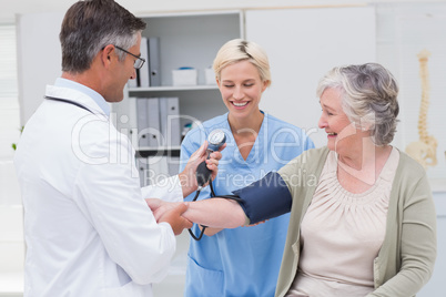 Doctor and nurse checking senior patients blood pressure