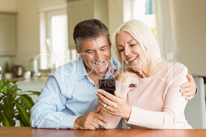Happy mature couple looking at smartphone together