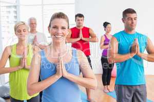 People meditating with hands joined in yoga class