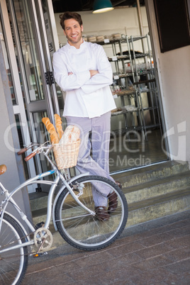 Smiling baker with arms crossed and bike
