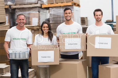 Volunteers smiling at camera holding donations boxes