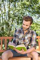 Handsome hipster reading in the park